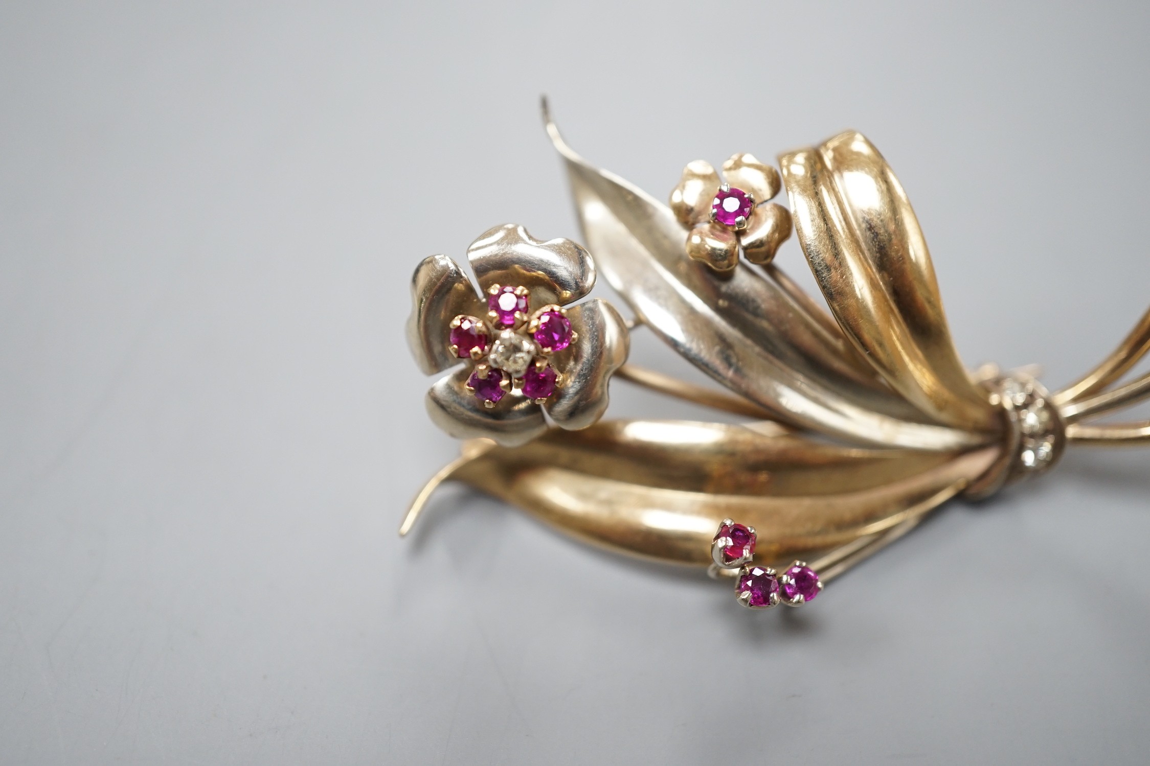 A two colour yellow metal, ruby and diamond cluster set floral spray brooch, 51mm, gross weight 8.2 grams.